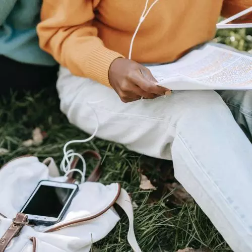 Student holding a research paper and a tablet